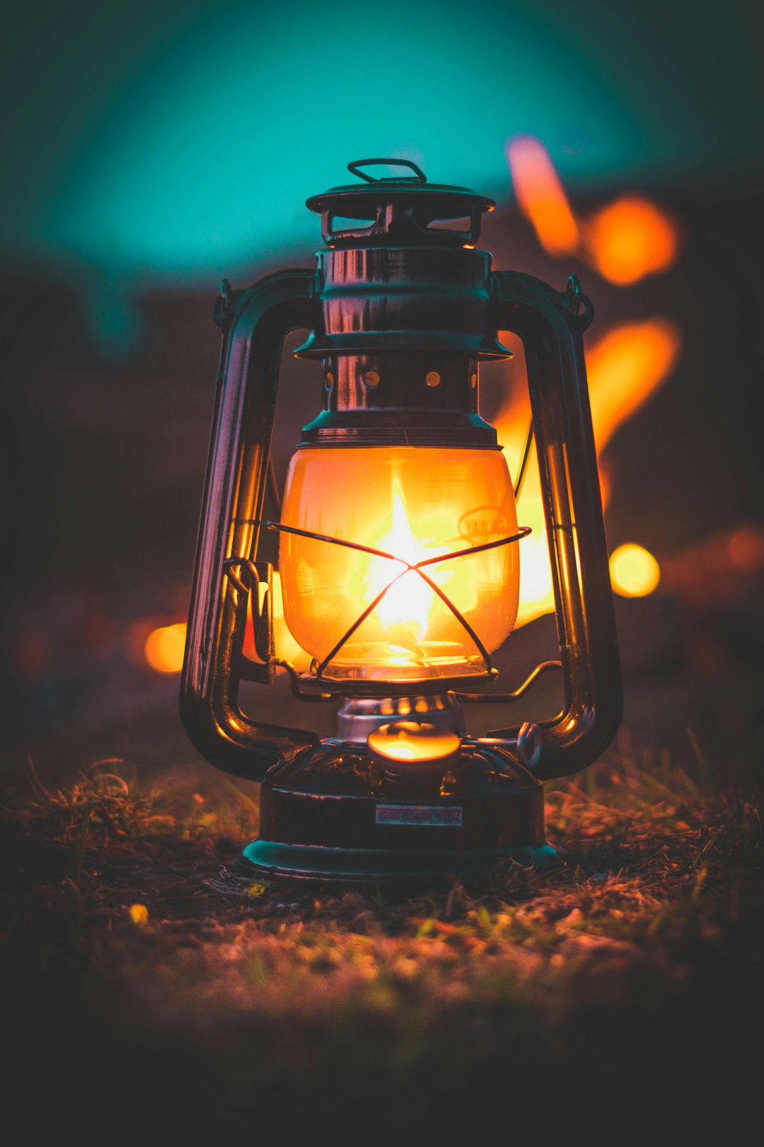 a lit lantern sitting on the grass in the evening