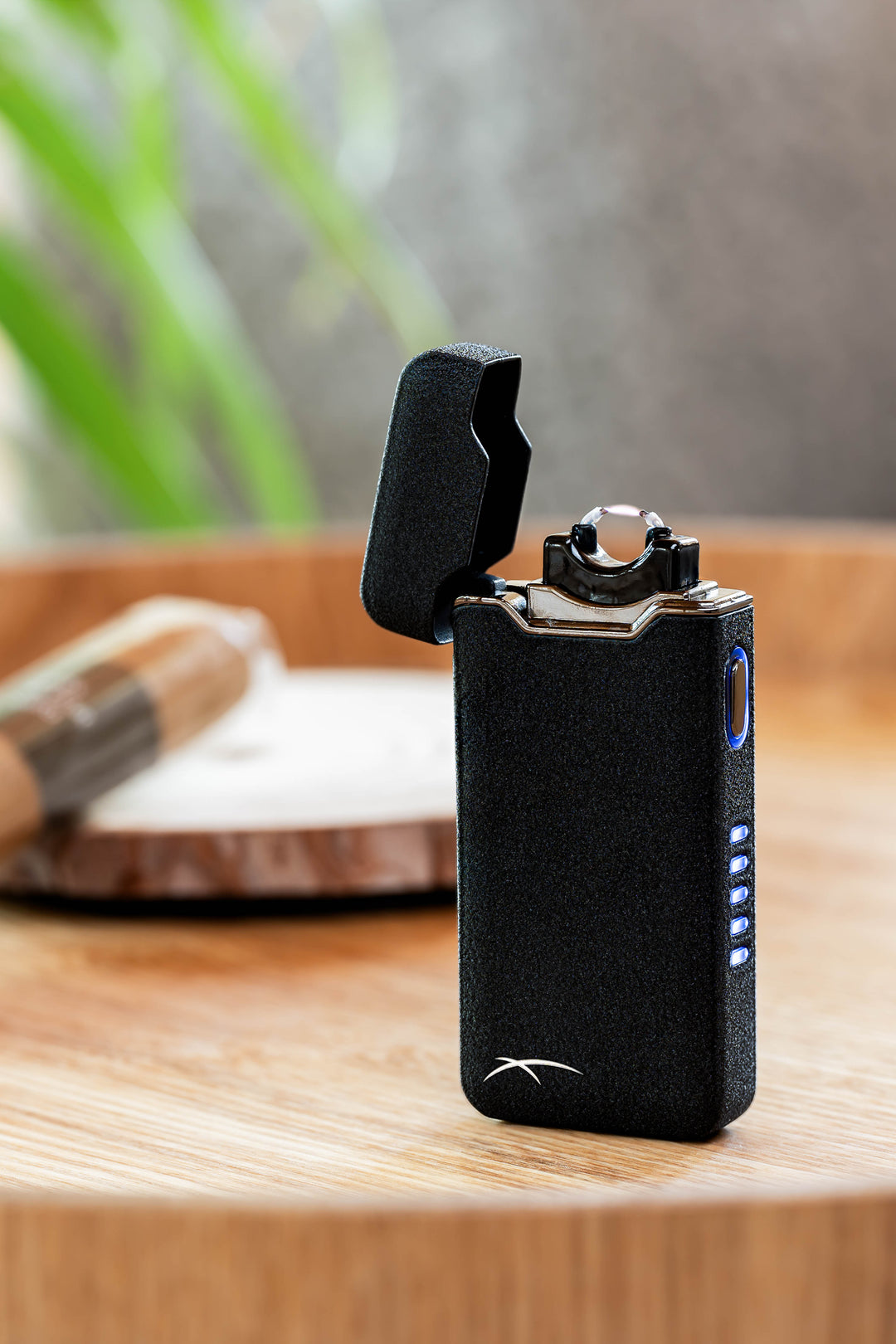 Black Flare lighter open and ignited on wooden table with cigar in background