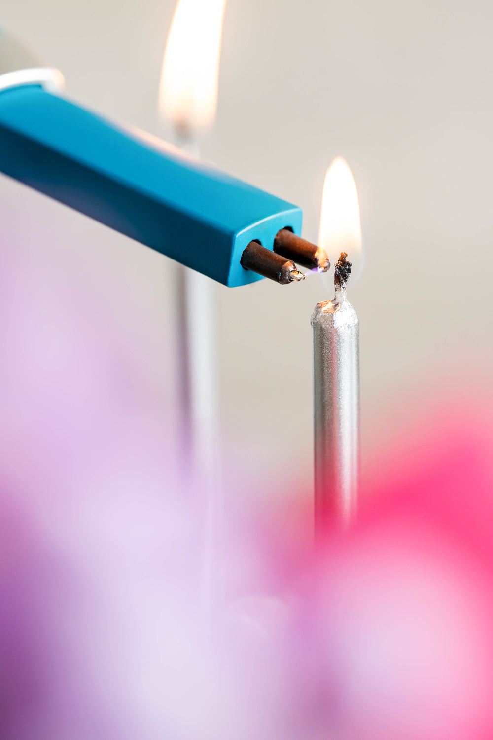 Sizzle Pitmaster USB rechargeable lighter in teal color lighting a silver candle