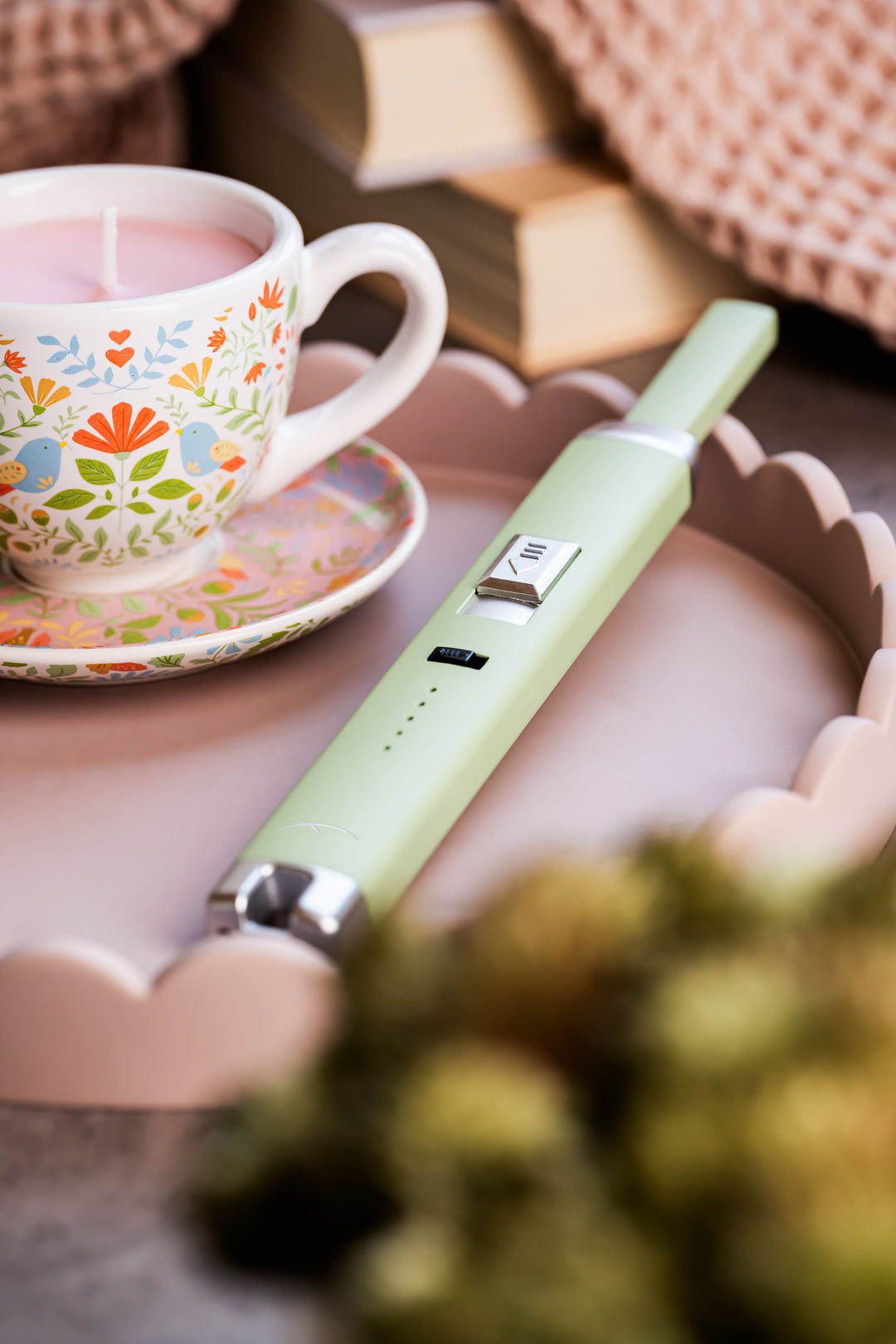 Sizzle Pitmaster USB rechargeable lighter in aloe color on a serving tray beside a teacup