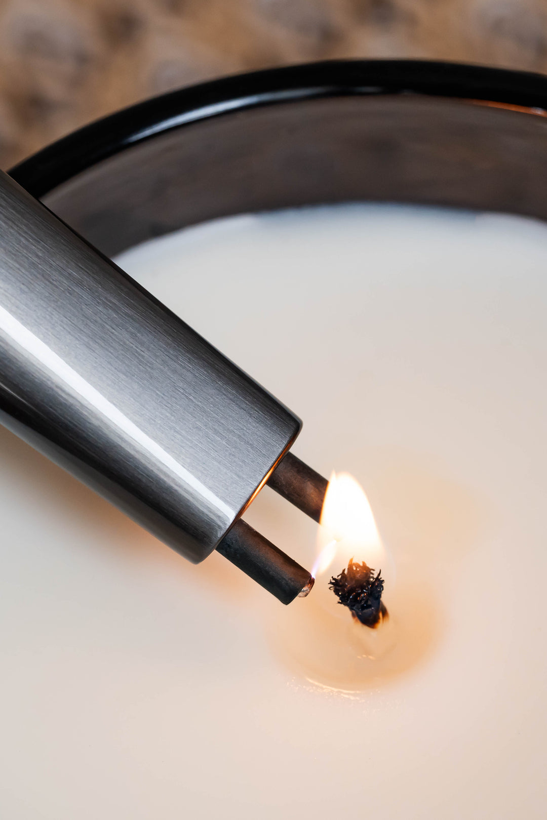 Sizzle Sleek USB rechargeable lighter with retractable prongs extended lighting a candle in a glass jar