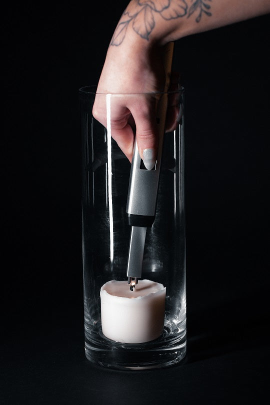 Sizzle Pitmaster USB rechargeable lighter held in a women's hand with a tattoo of a plant lighting a candle in deep vase