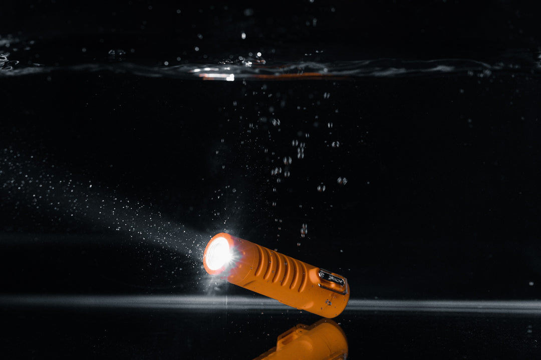 Sizzle Survival USB rechargeable lighter in orange waterproof casing underwater with flashlight turned on